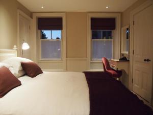 a bedroom with a bed and a desk and two windows at Houndgate Townhouse in Darlington