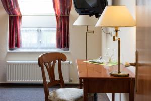 a desk with a chair and a lamp and a television at Hotel Garni Schlossgarten in Neustrelitz