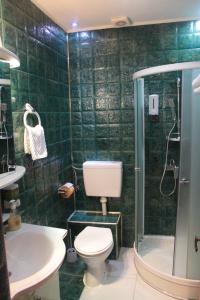 a green tiled bathroom with a toilet and a shower at Byblov Rooms Boutique in Bucharest