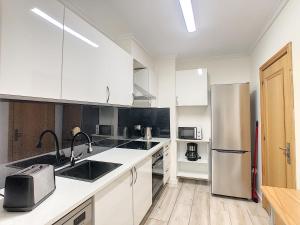 La cuisine est équipée de placards blancs et d'un réfrigérateur en acier inoxydable. dans l'établissement VeBella Ocean View by LovelyStay, à Caniço
