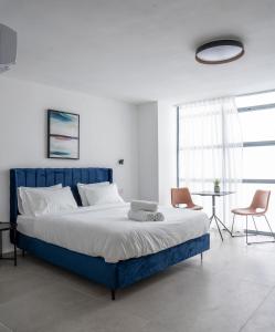 een slaapkamer met een blauw bed met 2 stoelen en een tafel bij De' Mar Florentine Hotel By Peraia in Tel Aviv