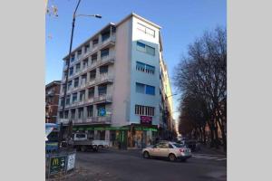 un edificio blanco alto en una calle de la ciudad con un coche en Appartamento Gisella, en Asti