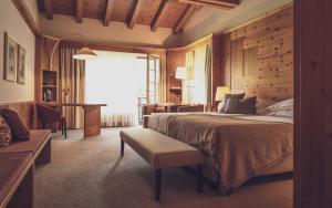 Schlafzimmer mit einem Bett, einem Tisch und einem Fenster in der Unterkunft Hotel Waldhuus in Davos