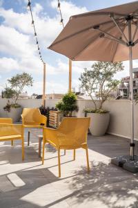 a patio with yellow chairs and an umbrella at De' Mar Florentine Hotel By Peraia in Tel Aviv