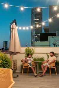 dos hombres sentados en una mesa sobre un techo en De' Mar Florentine Hotel By Peraia, en Tel Aviv