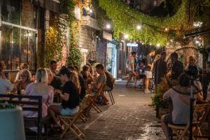 a group of people sitting in chairs in a street at night at De' Mar Florentine By Peraia in Tel Aviv