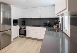 マスパロマスにあるRefurbished Seafront Apartmentの白いキャビネットとステンレス製の電化製品を備えたキッチン