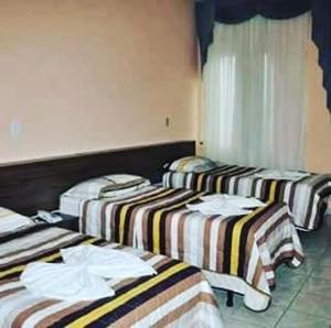 a group of three beds in a room at Hotel Meirelles in Montanha