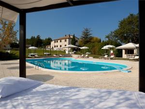 a large swimming pool with tables and umbrellas at Riserva Privata San Settimio in Arcevia