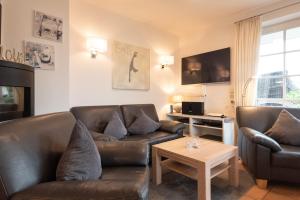 ein Wohnzimmer mit 2 Ledersofas und einem Tisch in der Unterkunft LH Dwarslöper, App 1 in Wenningstedt-Braderup