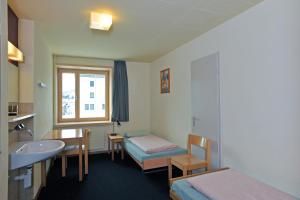 ein Hotelzimmer mit einem Waschbecken, einem Bett und einem Fenster in der Unterkunft St. Moritz Youth Hostel in St. Moritz