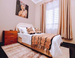 a bedroom with a bed and a dresser and a window at Casa del Court in Kampala