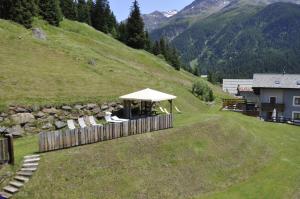 a gazebo on a hill next to a house at Hotel Nordik in Santa Caterina Valfurva