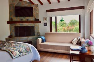 1 dormitorio con cama, sofá y chimenea en Sumangá Hotel Boutique en Sutatausa
