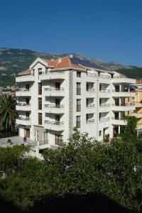 a large white apartment building with trees in front of it at Apartments Butua in Budva