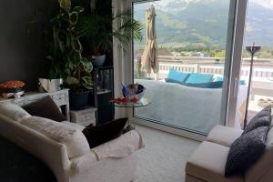 a living room with a couch and a table and a window at Penthouse with beautiful 360 terrace in Schaan
