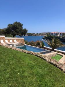 a swimming pool next to a body of water at Splendide Villa les pieds dans l'eau dans la baie de Mahon in Es Castell