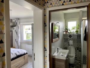 a bathroom with a sink and a bed and a mirror at La chambre Plume in Truchtersheim