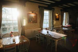 a dining room with tables and chairs and windows at The Powis Arms in North Lydbury