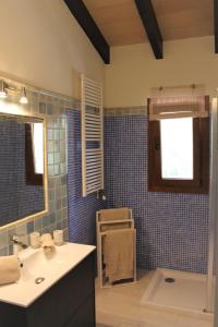 La salle de bains est pourvue de carrelage bleu, d'un lavabo et d'un miroir. dans l'établissement Villa Lara, à Sa Pobla