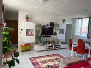 a living room with a tv and a table with red chairs at Camera Monica in Peschiera del Garda