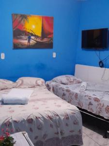 two beds in a room with a painting on the wall at Pousada Terra do Sol in Fortaleza