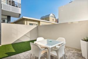 um pátio com uma mesa branca e cadeiras numa varanda em The Median Apartments em Joanesburgo