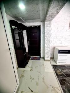 Cette chambre est dotée d'une porte noire et d'un sol en marbre blanc. dans l'établissement Топ Център едностаен!, à Razgrad
