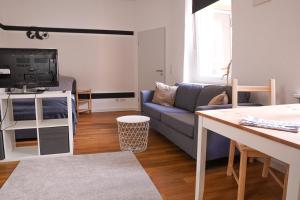 a living room with a blue couch and a tv at FULL HOUSE Studios - Panda Apartment - WiFi inkl in Halle an der Saale