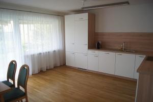 a kitchen with white cabinets and a wooden floor at Ferienwohnung Beate in Höchst