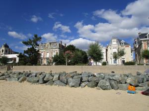 una pila de rocas en la playa con edificios en el fondo en Chambre d'hôte, Royan plage, petit-déjeuner bio, en Royan