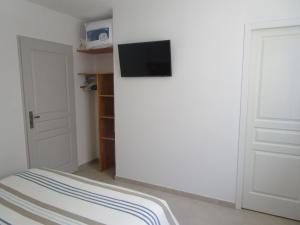 Habitación con pared blanca y TV en la pared. en Chambre d'hôte, Royan plage, petit-déjeuner bio, en Royan