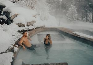 Ein Mann und eine Frau in einem Whirlpool mit Schnee in der Unterkunft Hotel Chateau Bromont in Bromont