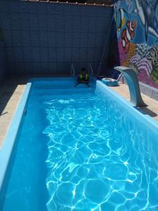 a large blue swimming pool with a person sitting in it at Casa Ubatuba Com Piscina in Ubatuba