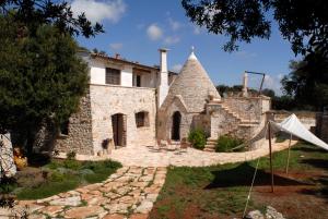 una vecchia casa in pietra con una tenda nel cortile di Masseria Iazzo Scagno a Martina Franca