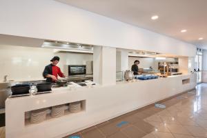 dwóch kucharzy przygotowujących jedzenie w dużej kuchni w obiekcie Grupotel Alcudia Suite w Playa de Muro