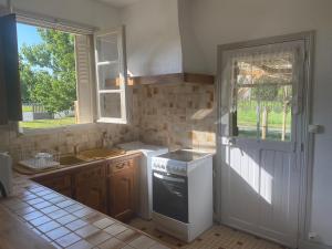 cocina con fogones, fregadero y ventana en Les roses de l'Olivier, en Les Rosiers