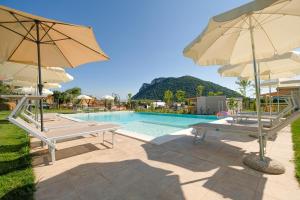 una piscina con 2 bancos y 2 sombrillas en Agricampeggio Le Corniole, en Affi