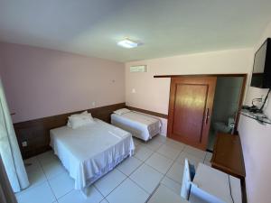 a hotel room with two beds and a television at Pousada Gruta in Ubajara