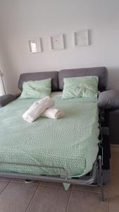 una cama de hospital con sábanas y almohadas verdes en queen’s paradise, en Callao Salvaje