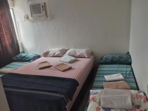 Dos camas en una habitación pequeña con toallas. en Nosso Canto, en Recife