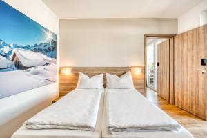 two beds in a room with a painting on the wall at COOEE alpin Hotel Kitzbüheler Alpen in Sankt Johann in Tirol