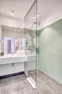 a bathroom with a glass shower and a sink at COOEE alpin Hotel Kitzbüheler Alpen in Sankt Johann in Tirol