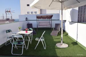 a balcony with a table and chairs and an umbrella at Atico Centro Historico in Cádiz