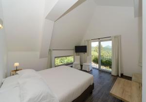 a white bedroom with a bed and a large window at Relais Chalons d’Orange in Pescasseroli