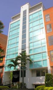 a tall building with a palm tree in front of it at Hotel Suite Comfort in Medellín