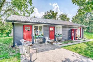 a small gray house with red doors and two chairs at Lighthouse Kitchen Suites near Auburn Waterloo I-69 Exit 334 in Auburn