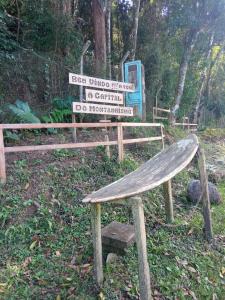 a wooden bench sitting in front of a sign at Conjugado Aconchegante em Teresópolis in Teresópolis