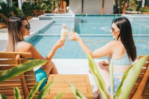 two women in bathing suits sitting by a pool drinking milkshakes at Bungalows Punta Uva in Puerto Viejo