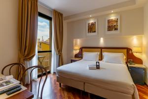a hotel room with a bed, desk, chair and lamp at Hotel Pitti Palace al Ponte Vecchio in Florence